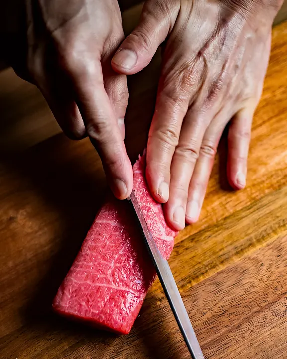 A chef slicing a block of tuna