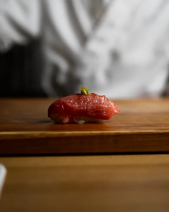 Tuna nigiri on the counter, chef behind