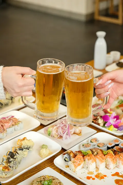 A beer toast over a table of sushi