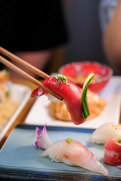 Tuna nigiri held in chopsticks