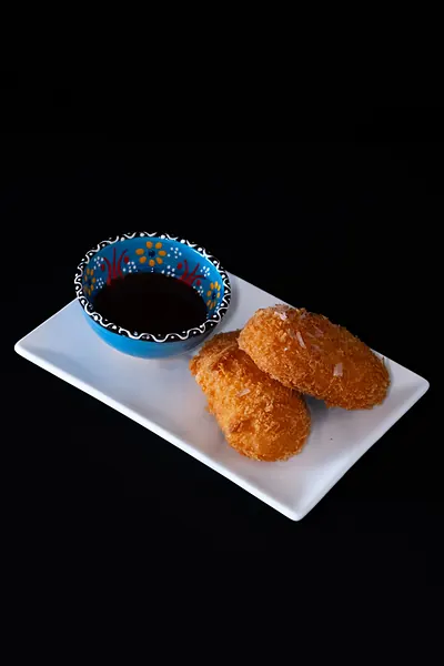 Two fried pieces with a dipping sauce
