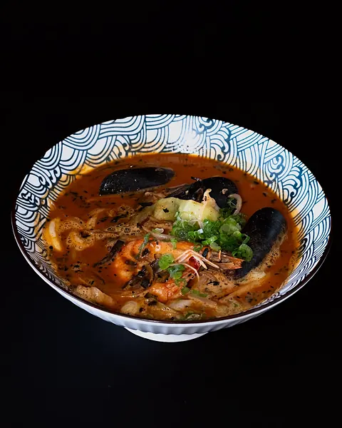 A bowl of noodle soup with seafood