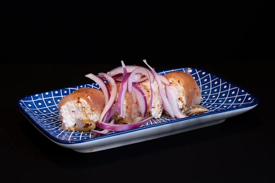 A roll topped with red onion on a blue plate