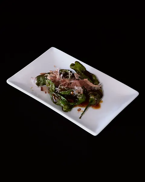 Blistered green peppers on a white plate