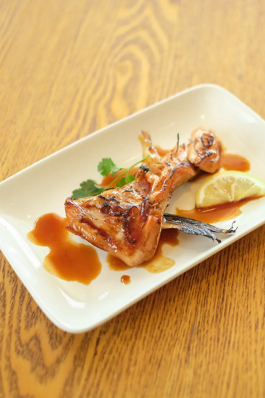 A grilled cut of fish with sauce and lemon