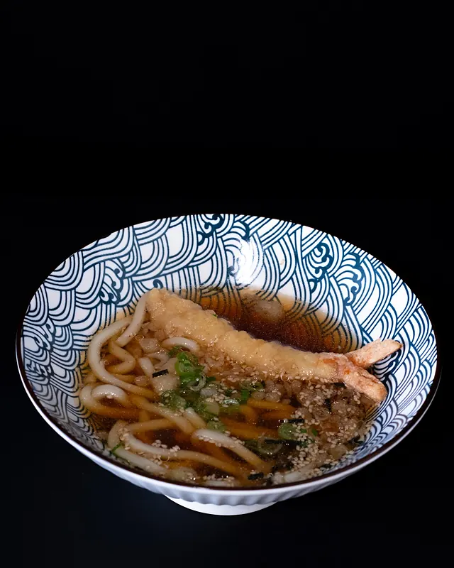 Udon with tempura in a dark bowl